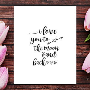 Puede incluir: Una tarjeta blanca con caligraf&iacute;a negra que dice "i love you to the moon and back" con una peque&ntilde;a flecha y corazones. La tarjeta est&aacute; rodeada de tulipanes rosas sobre un fondo de madera marr&oacute;n.