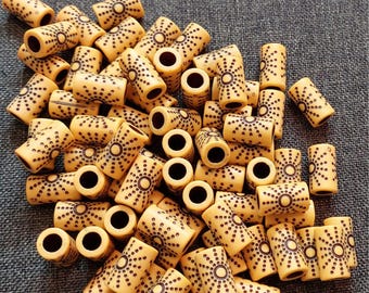 Puede incluir: Un montón grande de cuentas de madera amarillas con patrones de puntos marrones. Las cuentas son cilíndricas y tienen un agujero en el centro.