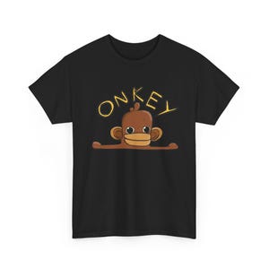 May include: A black short-sleeved t-shirt featuring a brown cartoon monkey graphic with large eyes and a wide mouth. Above the monkey, the word ONKEY is printed in a yellow, hand-drawn style font. The design is centred on the chest of the shirt.