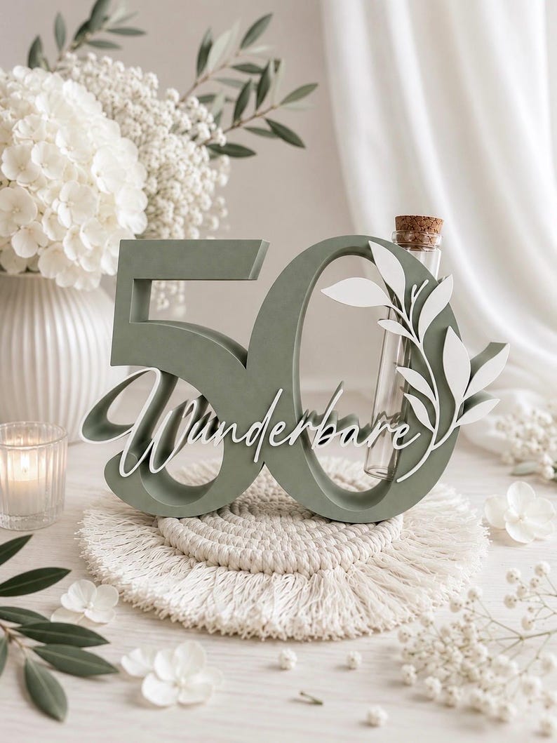 May include: A sage green wooden number 50 sign featuring the white cursive text "Wunderbare" and a white leaf cutout design. A clear glass test tube with a cork stopper is integrated into the number zero, providing a space for small floral stems.