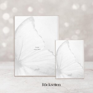 May include: Two white rectangular art prints, one large and one small, feature a butterfly wing design. The prints have the text "Du bist unser Gl&uuml;ck" and "R&uuml;ckseiten".