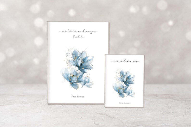 May include: Two white notebooks with watercolor floral designs. The larger notebook has the text "waterdraags hebt" and the smaller notebook has the text "inbless". Both notebooks feature blue flowers with gold accents.