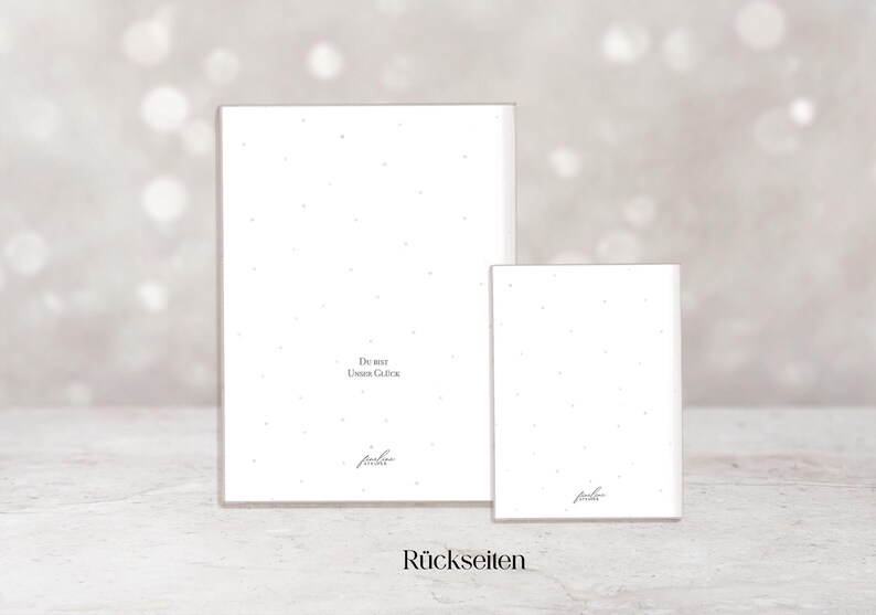 May include: Two white rectangular cards with a speckled pattern and text. The larger card has the text "Du bist Unser Gl&uuml;ck" and the smaller card has the same text. The word "R&uuml;ckseiten" is at the bottom.