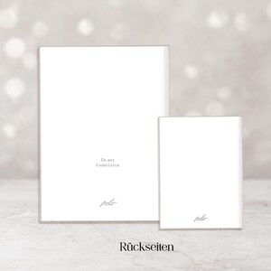 Op de afbeelding: Twee witte rechthoekige kaarten, de ene groter dan de andere, worden weergegeven tegen een zachte, vage achtergrond. De kaarten hebben tekst en een handtekening in het onderste gedeelte. Het woord "R&uuml;ckseiten" staat onderaan.