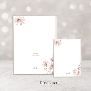 May include: Two white notepads with floral accents. The larger notepad has a rectangular shape, while the smaller one is square. Both have a watercolor floral design in the corners and the text "Du bist unser Gl&uuml;ck".