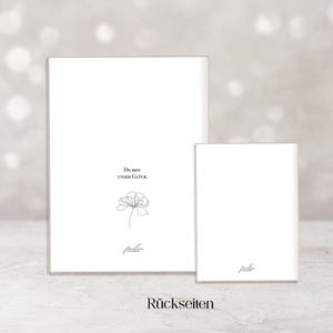 May include: Two white rectangular cards, one large and one small, are displayed against a soft, blurred background. The larger card features the text "Du bist unser Gl&uuml;ck" and a delicate floral illustration. The word "R&uuml;ckseiten" is at the bottom.