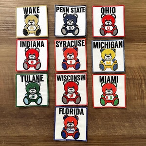 May include: Ten embroidered patches featuring teddy bears wearing different college team uniforms. The patches are white with black lettering and feature the following teams: Wake Forest, Penn State, Ohio State, Indiana, Syracuse, Michigan, Tulane, Wisconsin, Miami, and Florida.