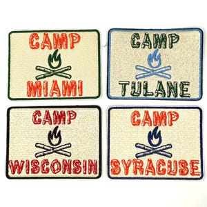 May include: Four embroidered patches with the word "CAMP" above a campfire graphic and a city name. The patches are rectangular with different colored borders and text: Miami, Tulane, Wisconsin, and Syracuse.