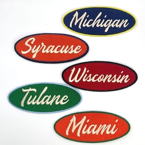 May include: Five embroidered oval patches with the names of US states and universities. The patches are in various colors: navy blue, orange, red, green, and orange. The names are in white script font.