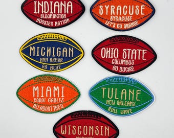 May include: A collection of embroidered football-shaped patches. Each patch features a team name and city, including Indiana, Syracuse, Michigan, Ohio State, Miami, Tulane, and Wisconsin. The patches are in various colors, with white text.