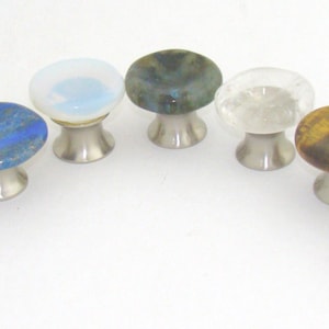 May include: Eight different gemstone cabinet knobs with a silver base. The gemstones are: rose quartz, lapis lazuli, opal, labradorite, clear quartz, tiger's eye, and citrine.