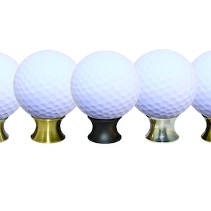 May include: Five golf ball cabinet knobs. Each white golf ball is mounted on a decorative base. The bases are in gold, silver, and black finishes. These knobs are ideal for a golf-themed room or furniture.