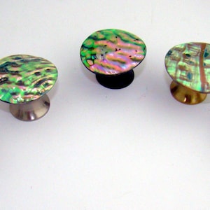May include: Five iridescent abalone shell cufflinks with a polished finish. The cufflinks have a round, oval, or irregular shape and are mounted on silver or gold-toned metal posts. The abalone shells display a range of colors, including green, pink, and blue.