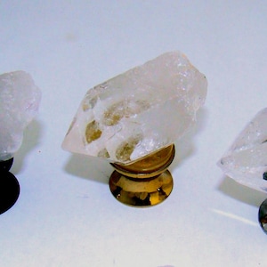 May include: Three clear quartz crystal knobs with varying base colors: black, gold, and silver. The quartz crystals are faceted and mounted on decorative bases, suitable for furniture or decor.