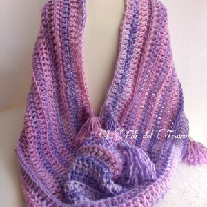 May include: A purple and pink crocheted scarf with fringe tassels. The scarf is made with a variegated yarn and has a simple stitch pattern.