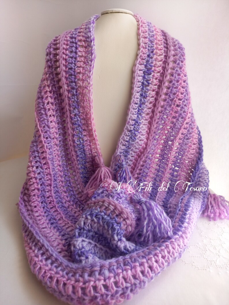 May include: A purple and pink crocheted scarf with fringe tassels. The scarf is made with a variegated yarn and has a simple stitch pattern.