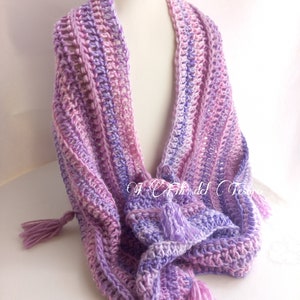 May include: A crocheted scarf with a gradient of pink and purple colors. The scarf has two tassels on the ends.