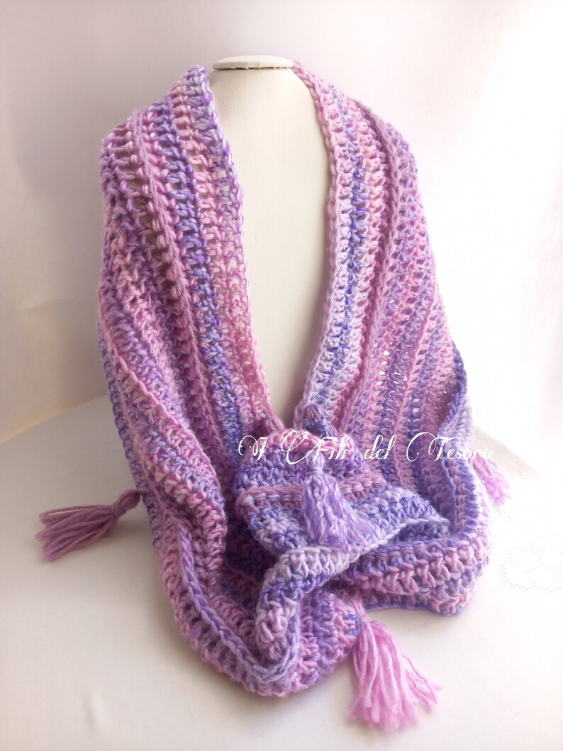 May include: A crocheted scarf with a gradient of pink and purple colors. The scarf has two tassels on the ends.