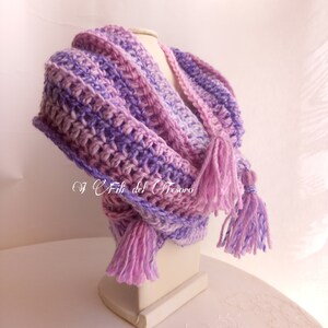 May include: A purple and pink crocheted scarf with long tassels. The scarf is displayed on a white mannequin.