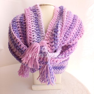 May include: A crocheted scarf in shades of pink and purple with long tassels. The scarf is displayed on a white mannequin.
