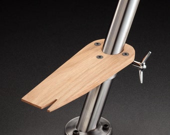 May include: A stainless steel and wood boat seat mount with a swiveling arm. The mount has a round base and a vertical post that extends upwards. The seat is made of wood and is attached to the post with a swiveling arm. The seat is angled downwards.