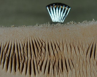 Op de afbeelding: Close-up van een lichtbruin lederen oppervlak met een reeks parallelle lijnen die erin zijn gedrukt. De lijnen zijn licht verhoogd en creëren een textuurpatroon.