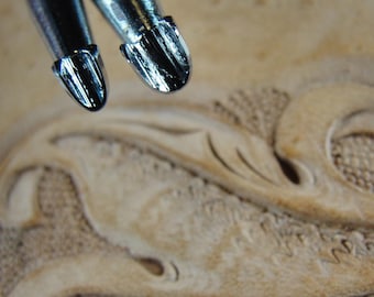 May include: Two close-up images of leather carving tools with a silver finish. The tools have different shaped tips, one is rounded and the other is pointed.