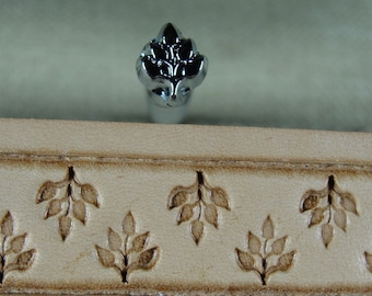 May include: A close-up of a leather stamping tool with a floral design. The tool is made of metal and has a polished finish. The tool is being used to create a pattern on a piece of leather.