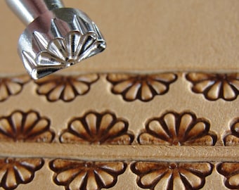 May include: A close-up of a leather stamping tool with a fan-shaped design. The tool is used to create decorative patterns on leather.