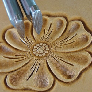 May include: Two metal leather stamping tools with a flower design stamped into leather.