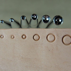 Peut inclure: Un ensemble de huit poin&ccedil;ons en m&eacute;tal pour cuir de diff&eacute;rentes tailles. Les poin&ccedil;ons sont dispos&eacute;s par ordre de taille, le plus petit &agrave; gauche et le plus grand &agrave; droite. Les poin&ccedil;ons sont tous de couleur argent et ont une finition lisse et polie.