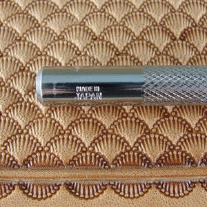 May include: A silver metal tool with a textured handle and the words "Made in Japan" engraved on the side.