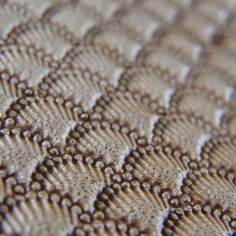 May include: Close-up of a textured, light brown surface with a repeating pattern of small, raised dots. The surface has a subtle, wavy appearance.