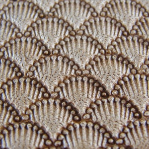 May include: Close-up of a textured surface with a repeating pattern of brown raised dots and lines. The surface has a light brown colour with a subtle sheen.