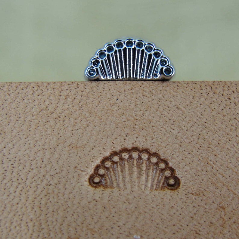 May include: A silver leather stamping tool with a half-circle design featuring a row of small circles along the edge.