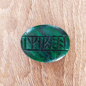 Op de afbeelding: Een groene steen met het woord "TRIPE" erin gegraveerd.