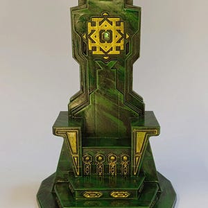 May include: A green and gold throne with a geometric design and a green gem in the center. The throne has a base with multiple steps.