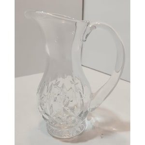 May include: A clear glass jug with a cut glass design. The jug has a round body and a handle.