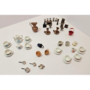May include: A collection of miniature dollhouse items including white ceramic tea sets with floral patterns, a copper-colored pitcher, metal candlesticks, small chairs, tables, a red bucket, woven baskets, and tiny metal pans on a white surface.