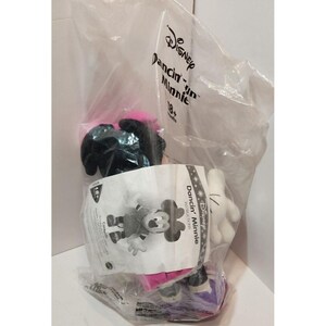 May include: A plush toy of Minnie Mouse in a pink and black outfit, with a white plush toy of Mickey Mouse's hand. The toys are packaged in a clear plastic bag with a white label that says "Disney Dancin' Minnie 18+ Months".