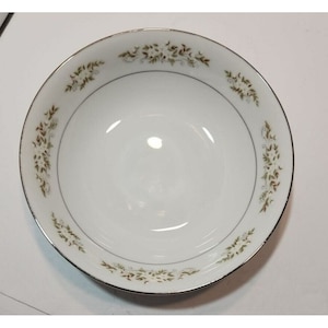 May include: White ceramic bowl with a green and brown floral pattern around the rim. The bowl has a silver trim.