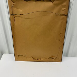 May include: The back of a brown wood picture frame with a brown paper backing and a wire hanger.