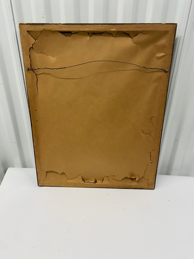 May include: The back of a brown wood picture frame with a brown paper backing and a wire hanger.