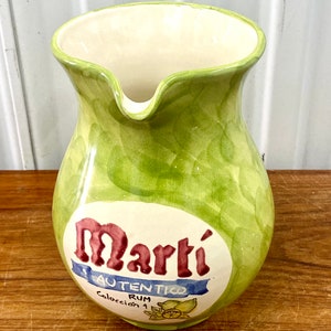 Può includere: Brocca in ceramica verde con interno bianco e un'etichetta che recita "Martí Auténtico Rum Colección 1".