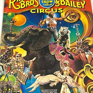 May include: A colorful vintage program for the Ringling Bros. and Barnum & Bailey Circus. The cover features a large elephant with a tiger on its back, a clown, and a group of performers. The text on the cover reads "Ringling Bros. and Barnum & Bailey Circus, The Greatest Show on Earth".