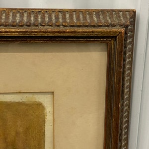 May include: A brown wooden picture frame with a gold-colored trim. The frame is empty and has a light brown mat.