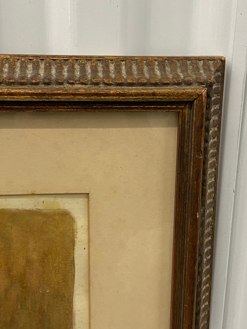 May include: A brown wooden picture frame with a gold-colored trim. The frame is empty and has a light brown mat.