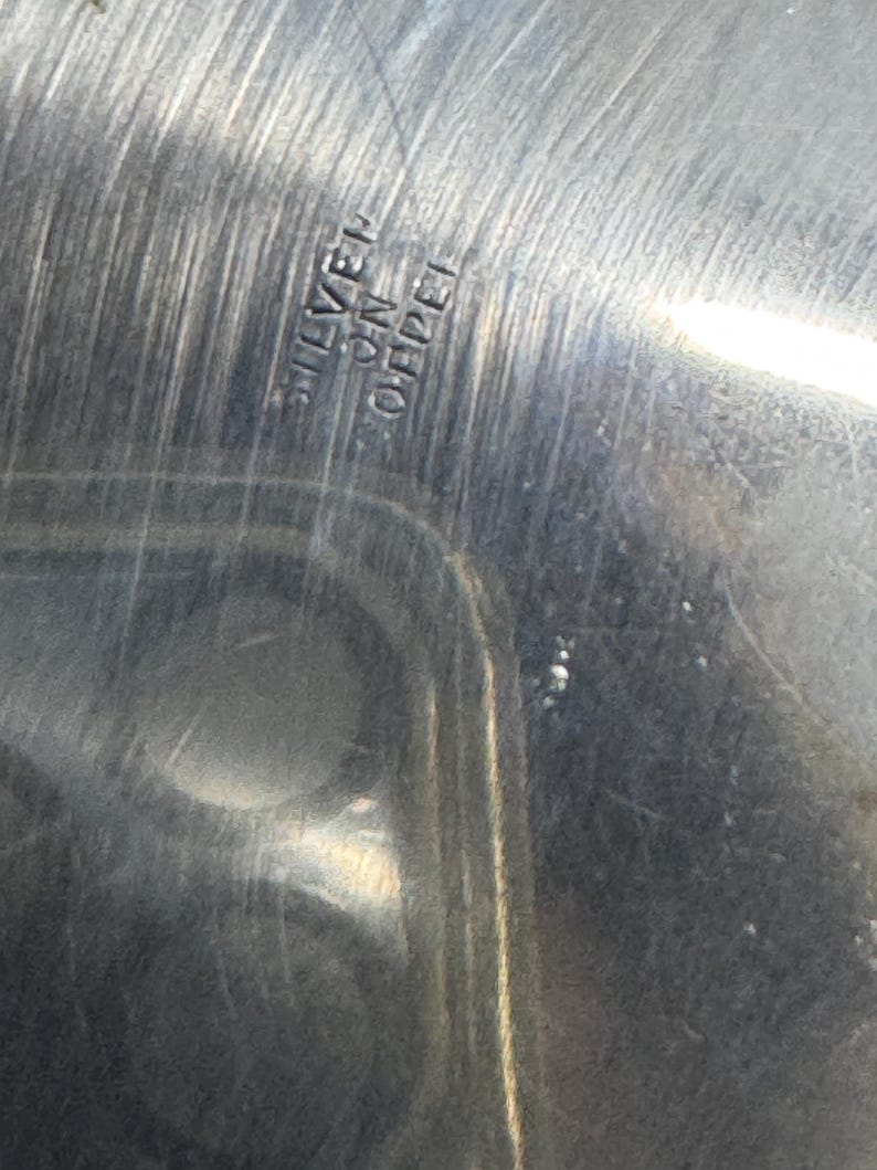 Puede incluir: Primer plano de una fuente de servir de plata con las palabras "SILVER ON COPPER" grabadas en la parte inferior.