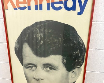 May include: A vintage framed poster featuring a black and white photo of John F. Kennedy. The poster has the word "Kennedy" in large, bold, red, blue, and orange letters.
