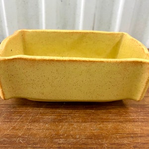 以下が含まれることがあります： 長方形で、わずかにざらざらした表面を持つ、黄色のセラミック製のプランターです。